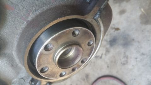 1996 Ford Bronco - A close-up view of a metal flange with threaded bolt holes, attached to a larger, rough-surfaced metal component, likely part of a vehicle'…
