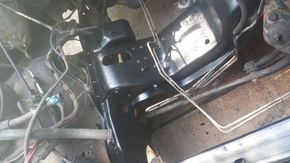 Underside of a vehicle frame with black paint, fuel lines, and wiring.
