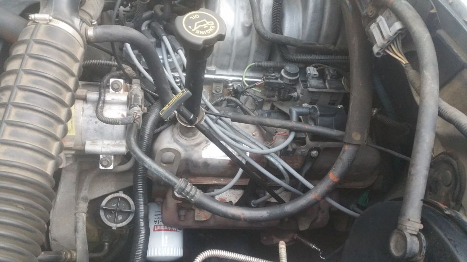 Engine bay of a 1996 Ford Bronco, showing air intake, oil cap, spark plug wires, and oil filter.