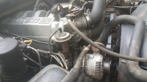 1996 Ford Bronco - Close-up view of the engine bay of a 1996 Ford Bronco, focusing on the intake manifold and alternator. The engine appears to be a V8 with p…