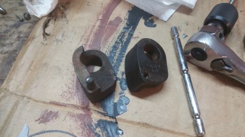 1996 Ford Bronco - Two rusty metal parts, possibly engine components, are laid out on a surface with a ratchet and extension. The parts have circular openings…