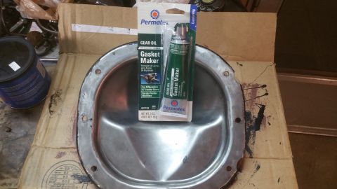1996 Ford Bronco - A Permatex Gear Oil Gasket Maker tube and a metal differential cover are laid out on a cardboard box.