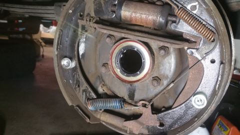 1996 Ford Bronco - A close-up view of the inside of a drum brake assembly, showing brake shoes, springs, and a wheel cylinder. A new seal is visible around th…