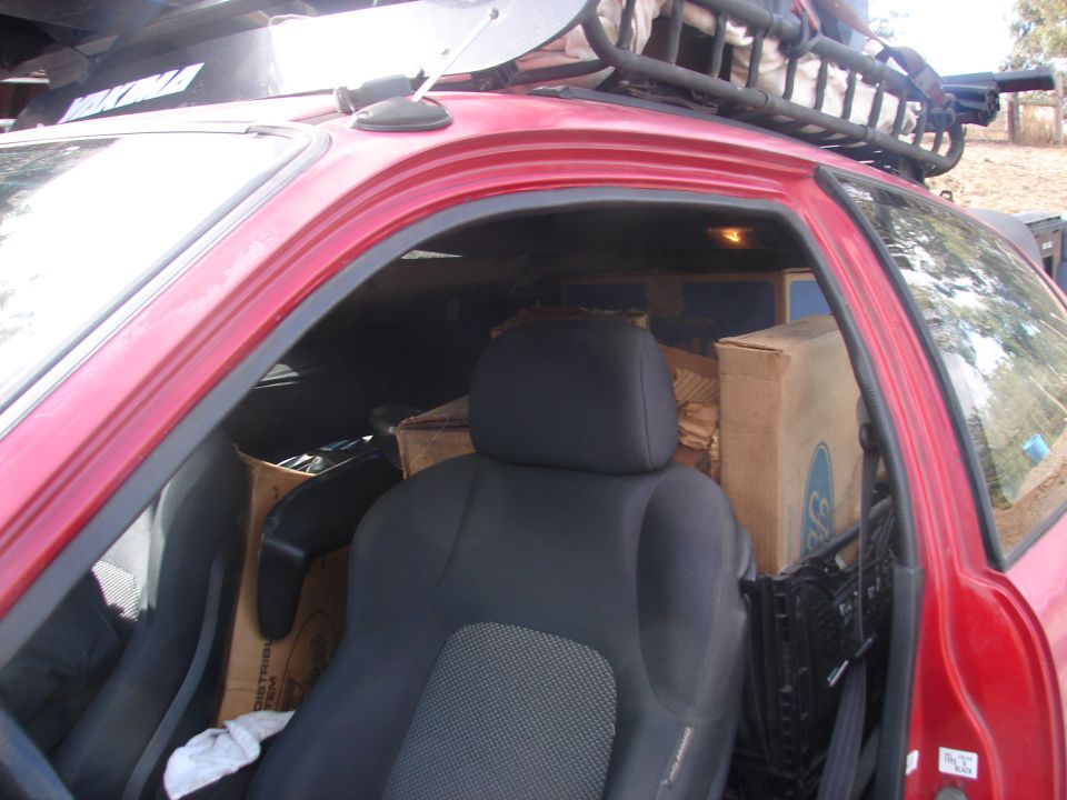 Interior of a red vehicle packed with boxes, showing a black seat and a roof rack.
