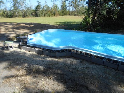 1992 Ford Bronco - A partially constructed above-ground swimming pool is surrounded by cinder blocks. The pool is filled with bright blue water and sits in a…