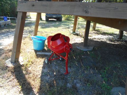 1992 Ford Bronco - A red cement mixer is parked on the ground next to a blue bucket under a wooden structure. A portion of a blue Ford Bronco is visible in th…