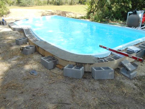 1992 Ford Bronco - A partially constructed swimming pool is surrounded by concrete blocks and rebar. A red level rests on the edge of the pool.