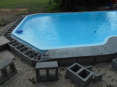 1992 Ford Bronco - A partially constructed swimming pool with blue water is surrounded by concrete blocks and rebar. The pool has a white coping and a blue po…