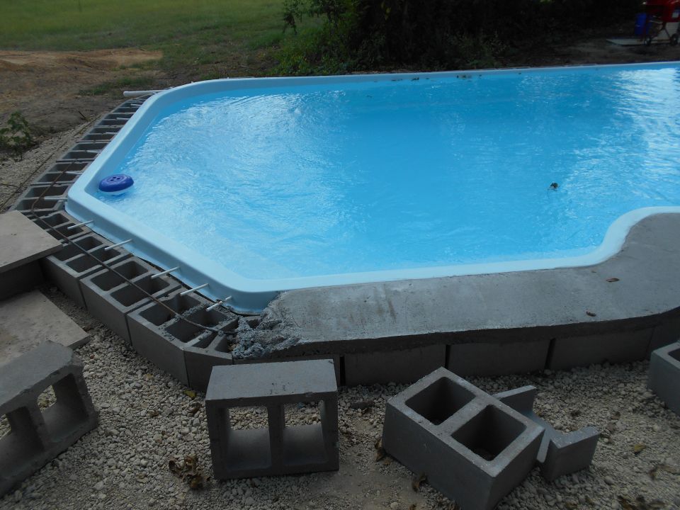 Partially constructed swimming pool with concrete blocks and rebar.