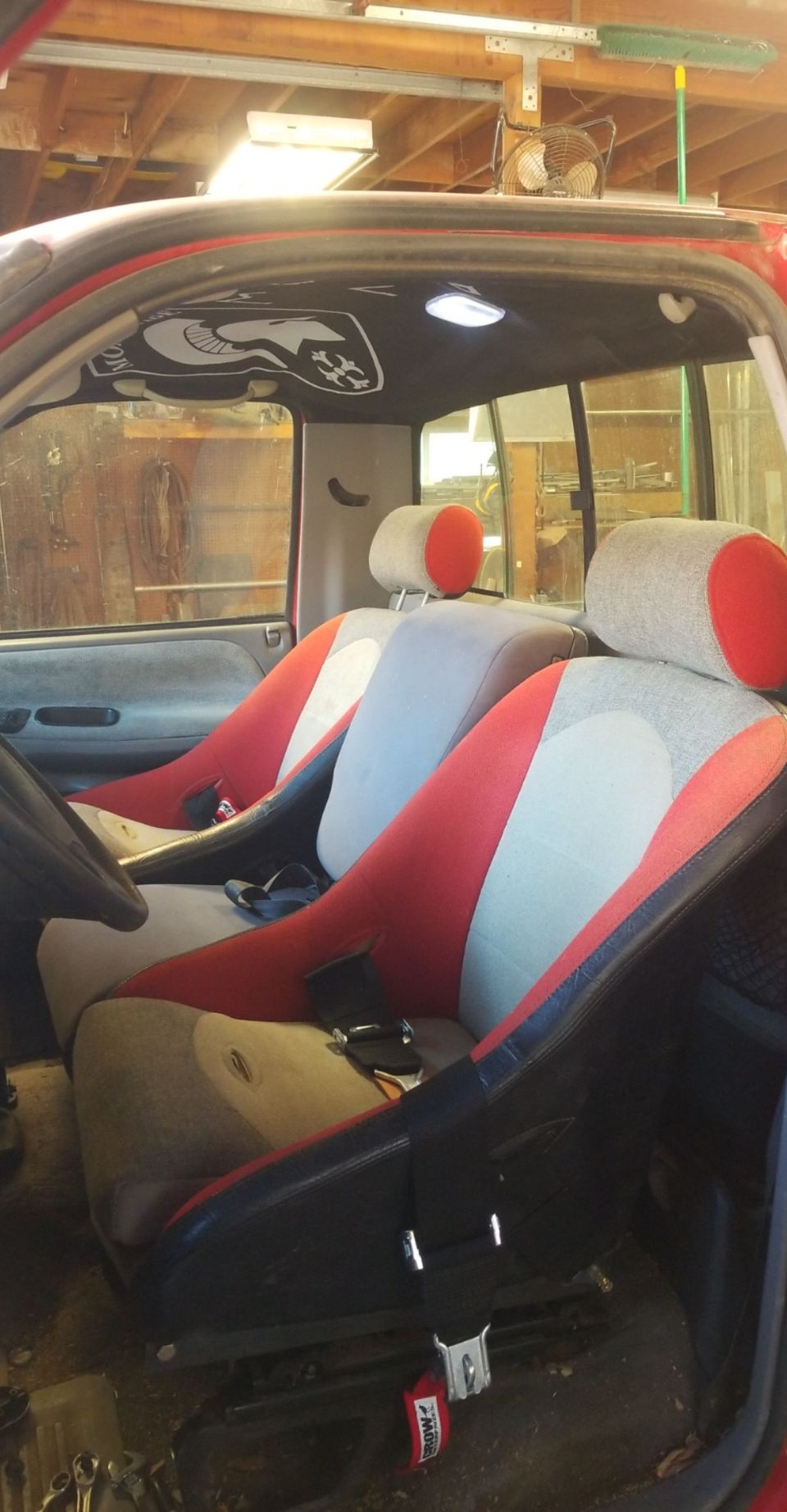 Interior of a red Dodge pickup truck with custom racing seats and graphic headliner.