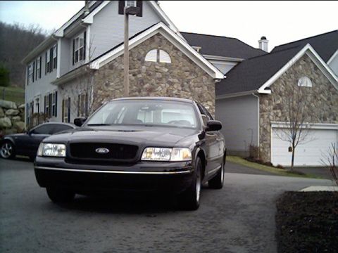 1999 Ford Crown Victoria - This black 1998 Ford Crown Victoria is parked in a driveway in front of a stone-accented house.