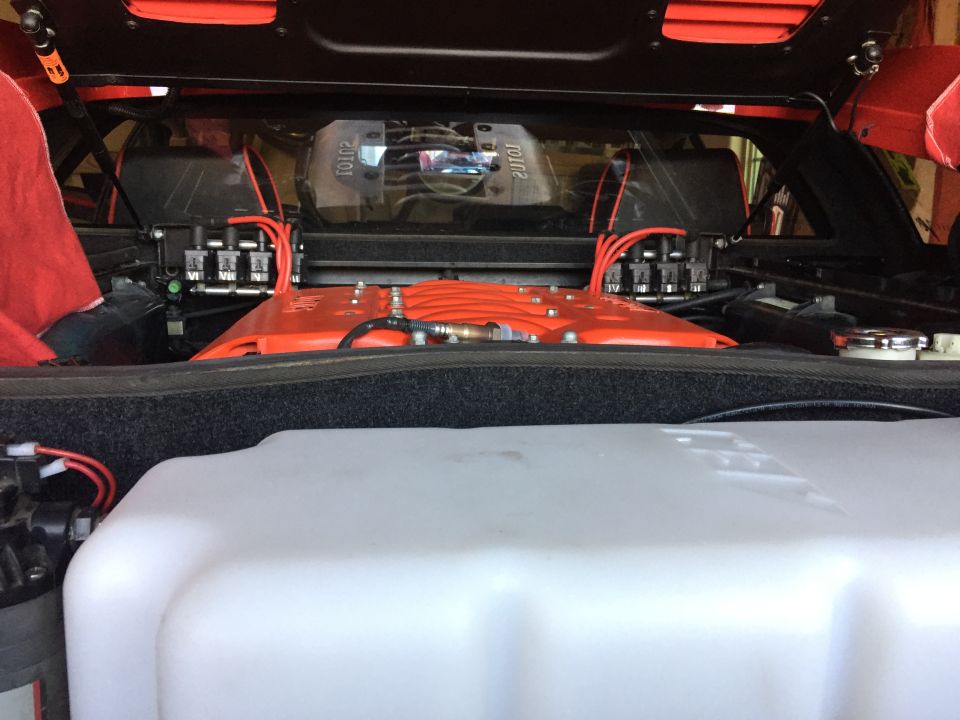 Lotus Esprit engine bay with orange cover, red wires, and white tank.