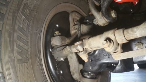 1996 Ford Bronco - A close-up view of the front suspension and steering components of a 1996 Ford Bronco, including the tire, tie rod ends, and steering linka…