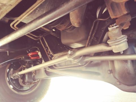 1996 Ford Bronco - Underside view of a vehicle's suspension system, showing the steering linkage, shock absorber, and part of the wheel and differential. The…