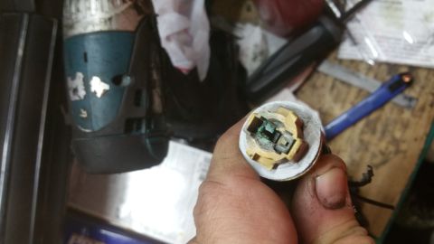 1996 Ford Bronco - A hand holds a corroded electrical connector with green oxidation on the metal contacts. In the background, a teal and black power tool is…