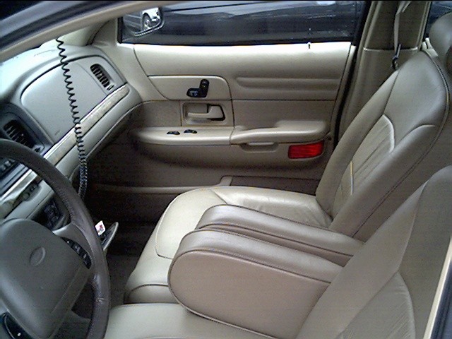 Interior shot of a car, showing the driver's side door panel, dashboard, steering wheel, and front seats