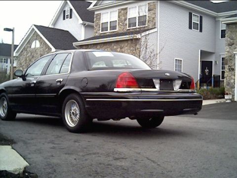 1999 Ford Crown Victoria - Rear view of a black 1999 Ford Crown Victoria sedan parked in a driveway.
