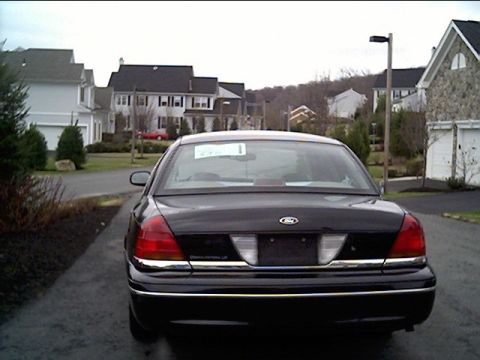 1999 Ford Crown Victoria - Rear view of a black 1999 Ford Crown Victoria parked in a suburban driveway.