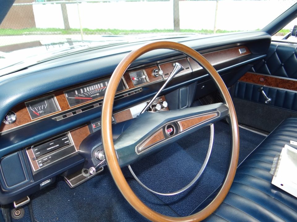 Dark blue vintage car interior with woodgrain dash trim and large wood-rimmed steering wheel