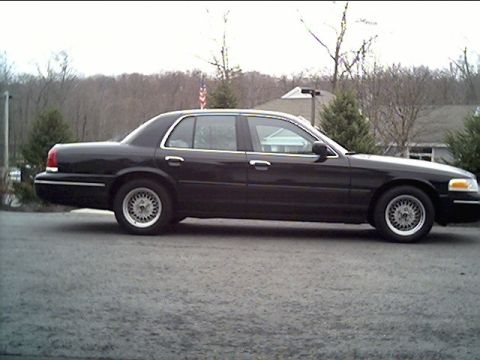 1999 Ford Crown Victoria - This black 1998 Ford Crown Victoria sedan is shown from the side.