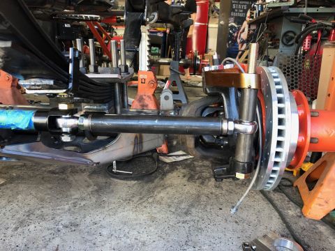1992 Jeep Wrangler - A close-up view of a vehicle's suspension and braking system, showing a disc brake rotor, caliper bracket, and part of the steering linkage…