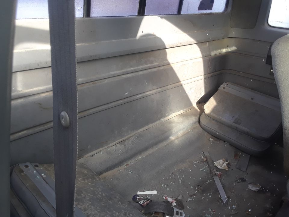 Interior of a vehicle showing a dirty floor with debris and a seatbelt.