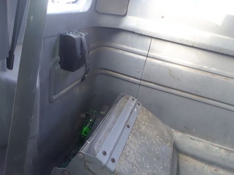1994 Ford Bronco - Interior view of a gray vehicle, possibly a 1994 Ford Bronco, showing a broken green bottle on the floor and a black storage compartment mo…