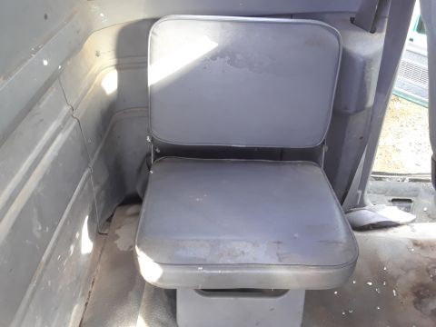 1994 Ford Bronco - The interior of a vehicle shows a gray vinyl jump seat with a swivel base. The seat is positioned next to a gray interior wall with sunligh…