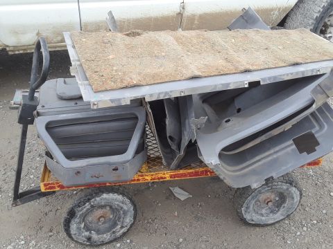 1994 Ford Bronco - A yellow and red utility cart is loaded with various gray plastic automotive interior door panels and a piece of carpet padding. The cart h…