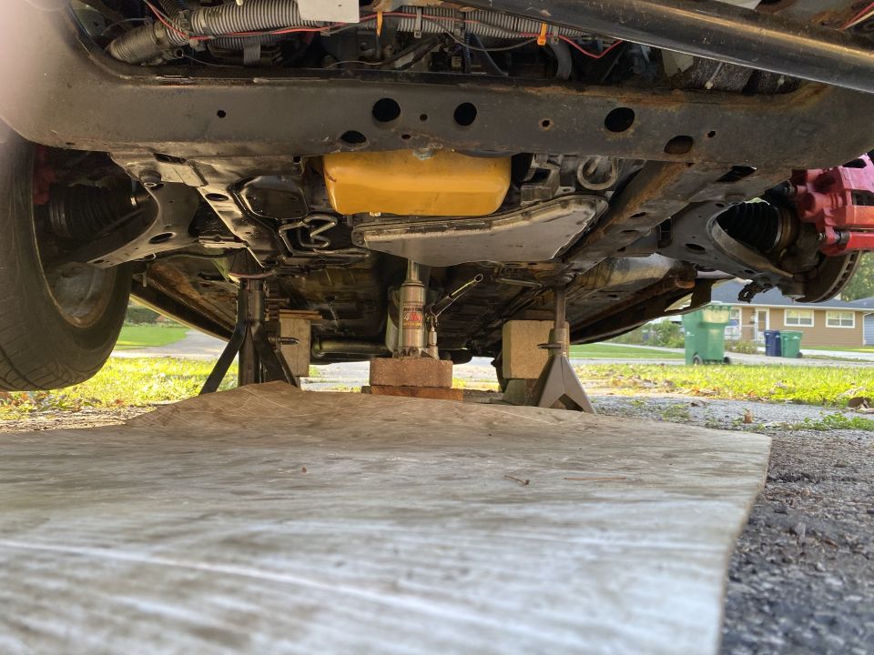 Underside of a vehicle on jack stands, showing suspension and exhaust components.