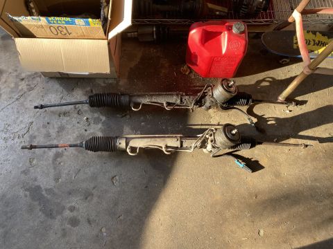 Two power steering rack and pinion assemblies on a concrete floor.