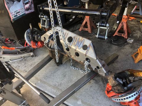 1992 Jeep Wrangler - A custom-fabricated suspension component, likely for an off-road vehicle, is suspended by chains and mounted on a metal frame. The componen…