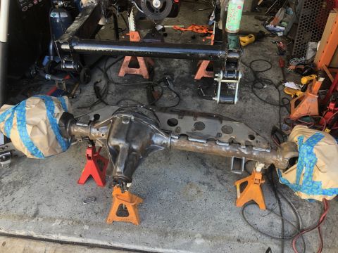 1992 Jeep Wrangler - A heavy-duty rear axle assembly, likely from a Jeep Wrangler, is supported by jack stands in a garage setting. The axle appears to be under…