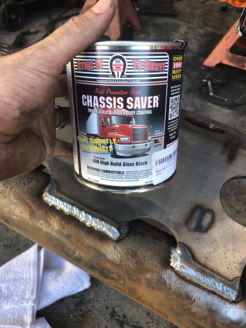 1992 Jeep Wrangler - A hand holds a can of "CHASSIS SAVER" rust preventive paint over a metal part with visible welds. The can is labeled "STICK-IT TO-RUST!" an…