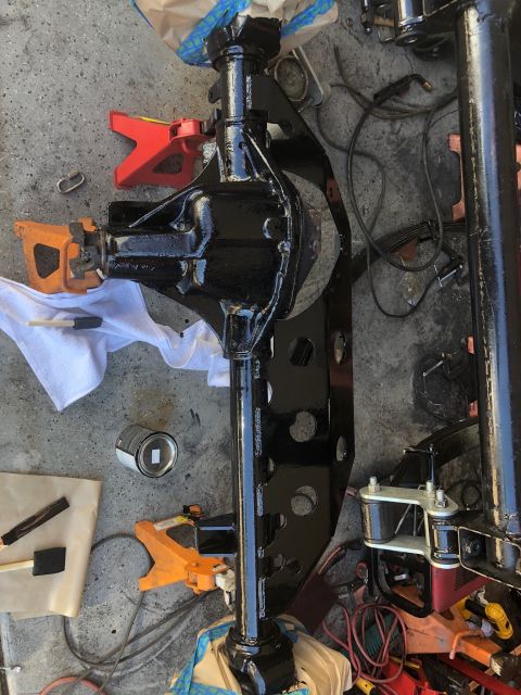 1992 Jeep Wrangler - A black painted front axle assembly, likely for a Jeep Wrangler, is shown resting on jack stands. Tools and a can of paint are visible on t…