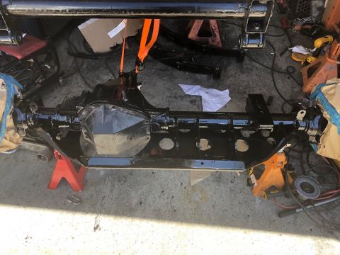 1992 Jeep Wrangler - A black painted rear axle assembly, likely from a Jeep Wrangler, is supported by red and orange jack stands on a concrete surface. The asse…