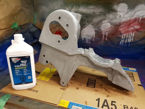 1978 Ford Bronco - A bottle of BDR Metal Prep is shown next to a silver-colored metal part. The background appears to be a drop cloth with spray paint on it.