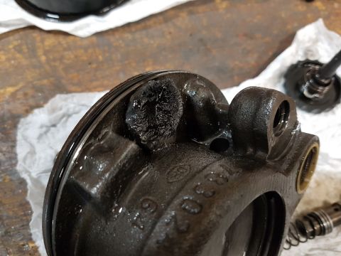 1978 Ford Bronco - A close-up view of a heavily corroded and damaged metal brake caliper part, likely from a vintage vehicle, resting on a white cloth. The pa…