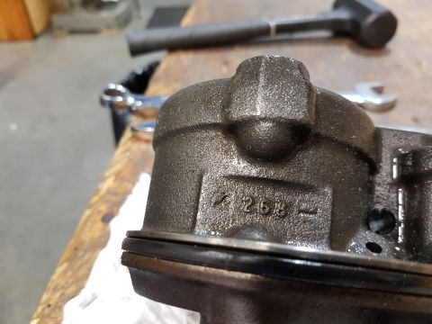 1978 Ford Bronco - A close-up, angled view of a dark gray, cast metal automotive part with the numbers "258" stamped into its side. The part has a black rubbe…