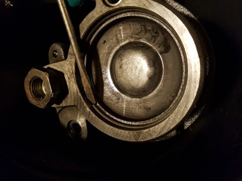 1978 Ford Bronco - A close-up view of a metal component, possibly a brake caliper or master cylinder, with a nut and bolt visible. A tool is inserted into the…