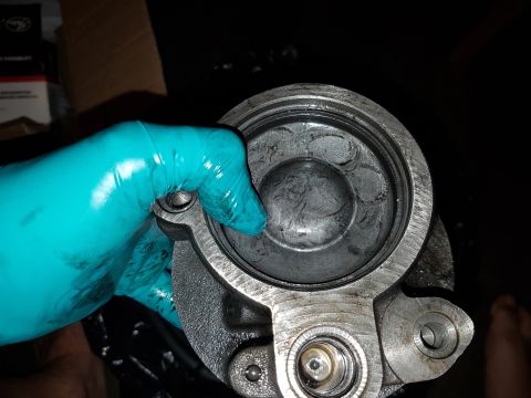1978 Ford Bronco - A gloved hand holds a disassembled brake caliper, revealing the cylinder bore with visible scoring and wear marks.