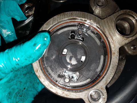 1978 Ford Bronco - A close-up view of a disassembled automotive part, possibly a pump or valve assembly, with a hand wearing a teal glove holding it. The part…
