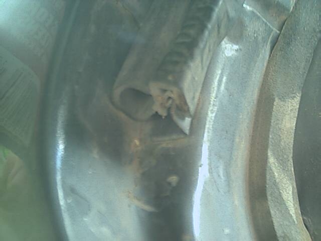 Close-up of cut rubber weatherstrip seal end in a rusty painted body channel