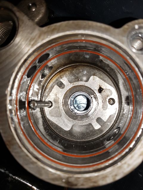 1978 Ford Bronco - A close-up, top-down view of the internal components of a metal mechanism, possibly a pump or valve, with an orange O-ring visible.