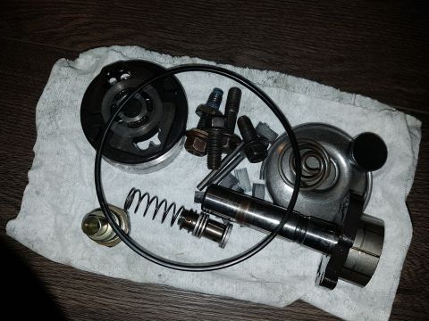 1978 Ford Bronco - A collection of disassembled engine or transmission parts, including bolts, springs, a camshaft, and a circular gasket, are laid out on a w…