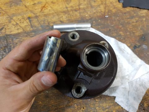 1978 Ford Bronco - A person holds a metal socket over a dark brown metal part that appears to be a hub or brake component. Another metal cylinder is visible i…