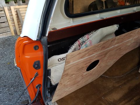 1978 Ford Bronco - The rear passenger side of an orange and white utility vehicle with a custom wooden panel installed inside the cargo area. A burlap sack wi…