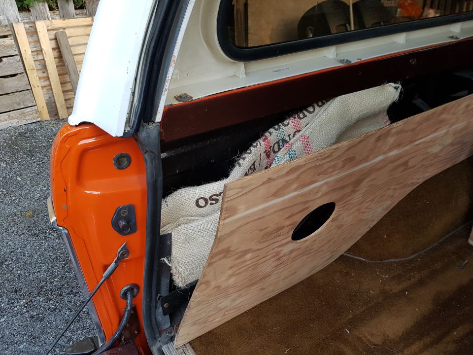Rear passenger side of an orange and white utility vehicle with custom wood panel and burlap sack.