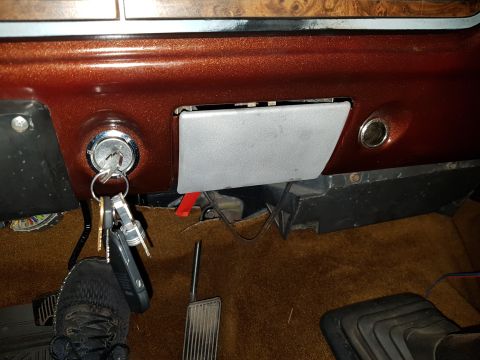 1978 Ford Bronco - A close-up interior shot shows a set of keys in the ignition of a vintage vehicle. The dashboard has a metallic brown finish, and the floor…