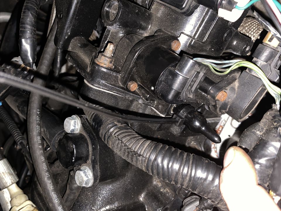 Black plastic sensor with wire on engine component